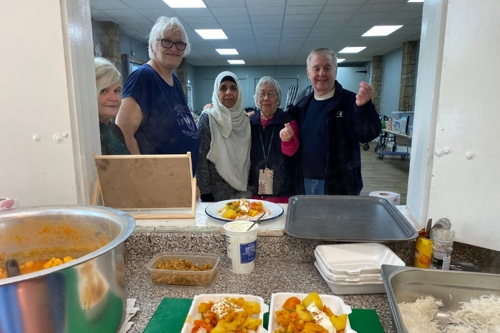 Tooting Community Kitchen guests smile as they wait for lunch